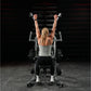 Woman performing wide pulldown exercise on Hammer Strength plate-loaded machine, arms raised overhead gripping handles, weari