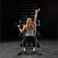 Woman performing wide pulldown exercise on Hammer Strength machine in gym setting, wearing gray tank top and black leggings