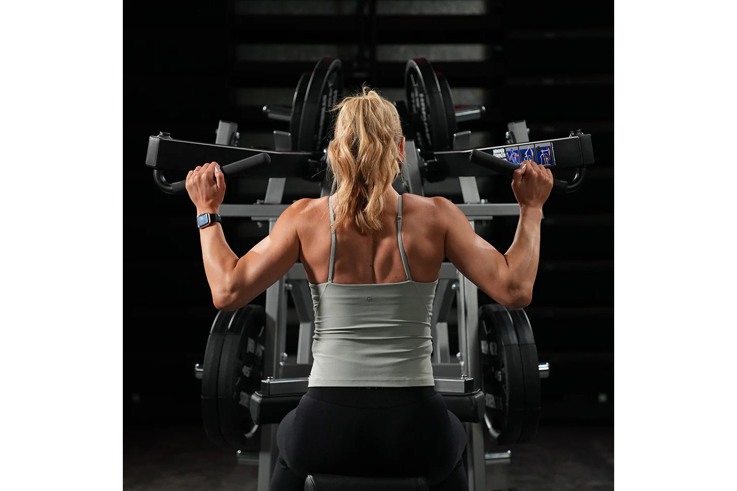 Woman lifting weight on hammer strength plate-loaded iso-lateral wide pulldown machine in gym setting