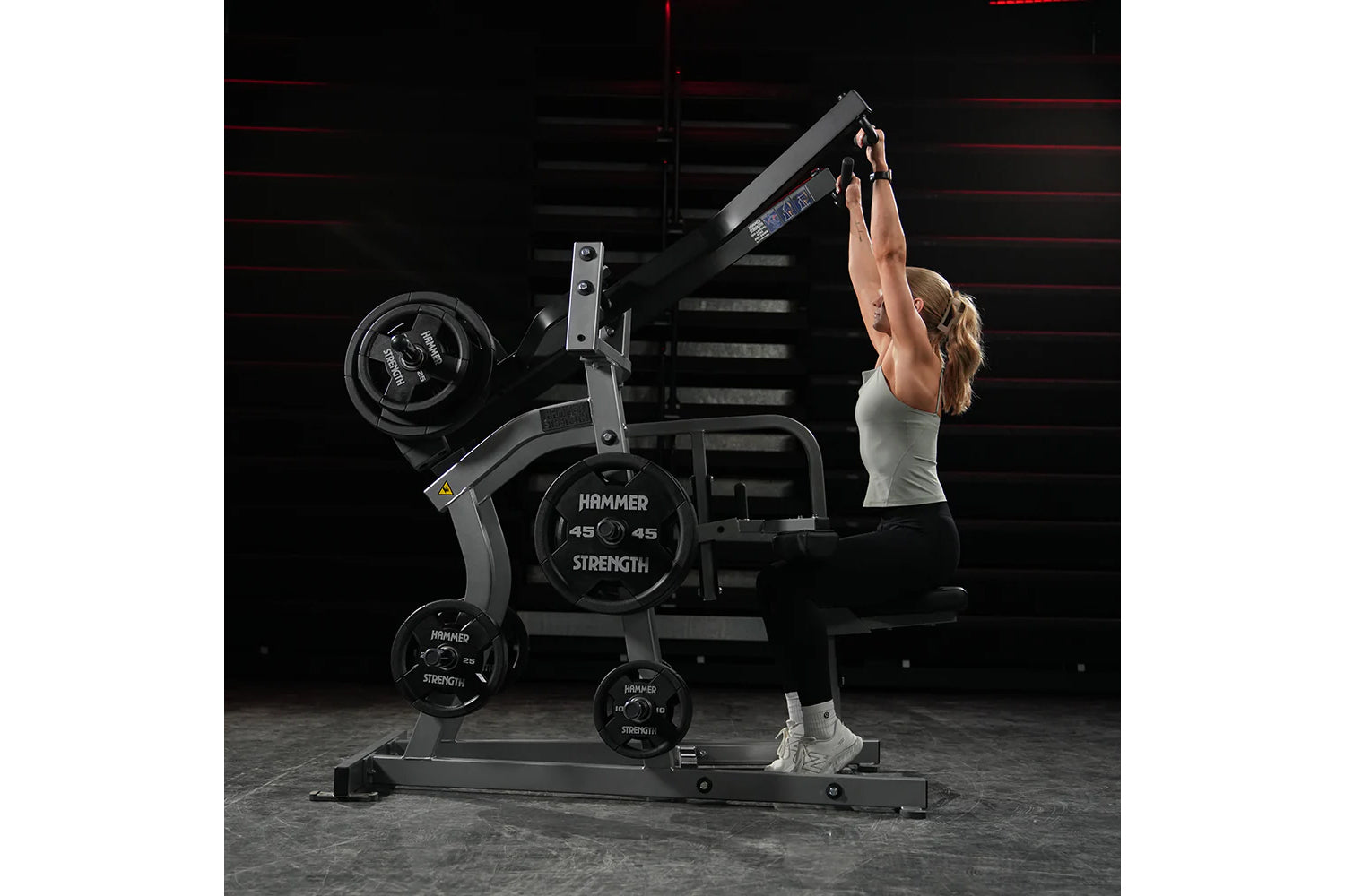 Hammer Strength plate-loaded iso-lateral wide pulldown machine with black frame and weight plates, model shown in use by woma