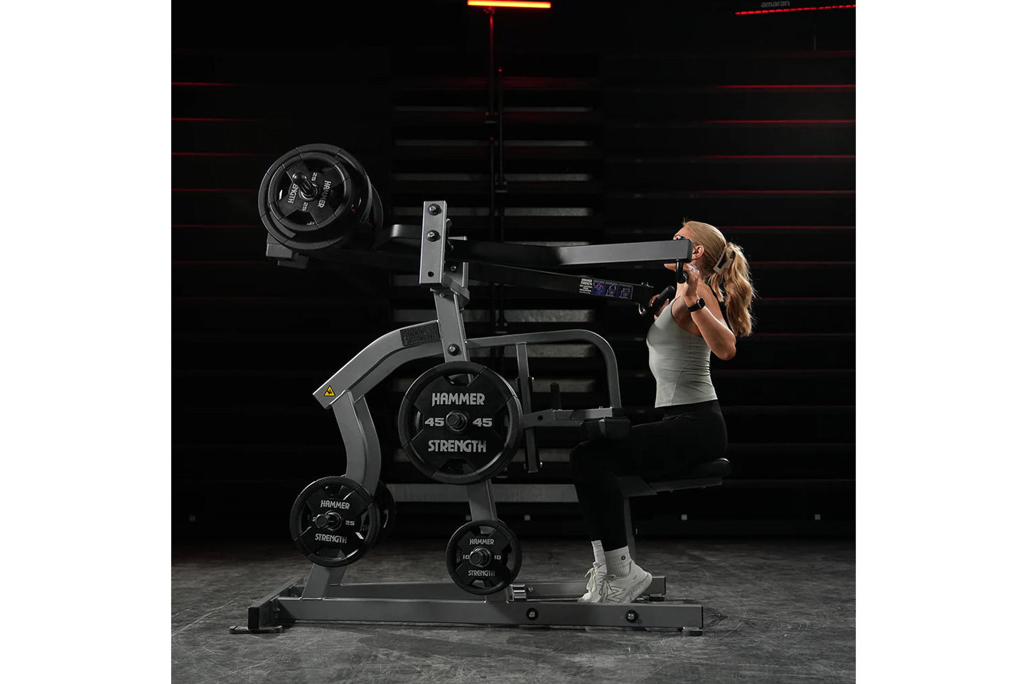 Woman using black Hammer Strength plate-loaded iso-lateral wide pulldown machine with weight plates in gym setting