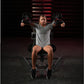 Woman performing lateral raise exercise on black Hammer Strength plate-loaded machine, holding dumbbells with arms extended, 
