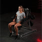 Woman wearing gray t-shirt using black plate-loaded lateral raise exercise machine in gym setting