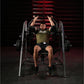 Man in olive t-shirt performing plate-loaded pullover exercise on Hammer Strength machine with red background