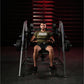 Man wearing olive Hammer Strength t-shirt using plate-loaded pullover machine in gym setting with red lighting