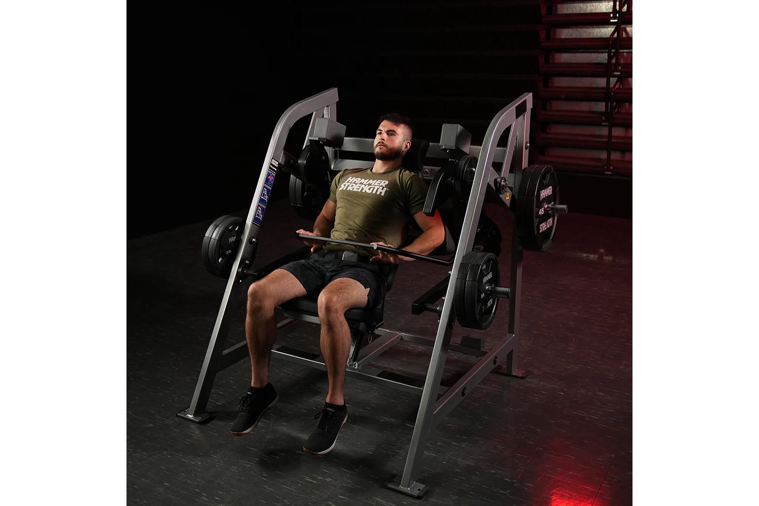 Man using gray Hammer Strength plate-loaded pullover machine in gym, wearing olive green t-shirt and black shorts