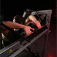 Man using burgundy Hammer Strength plate-loaded pullover machine with chest pad, demonstrating exercise position on black bac