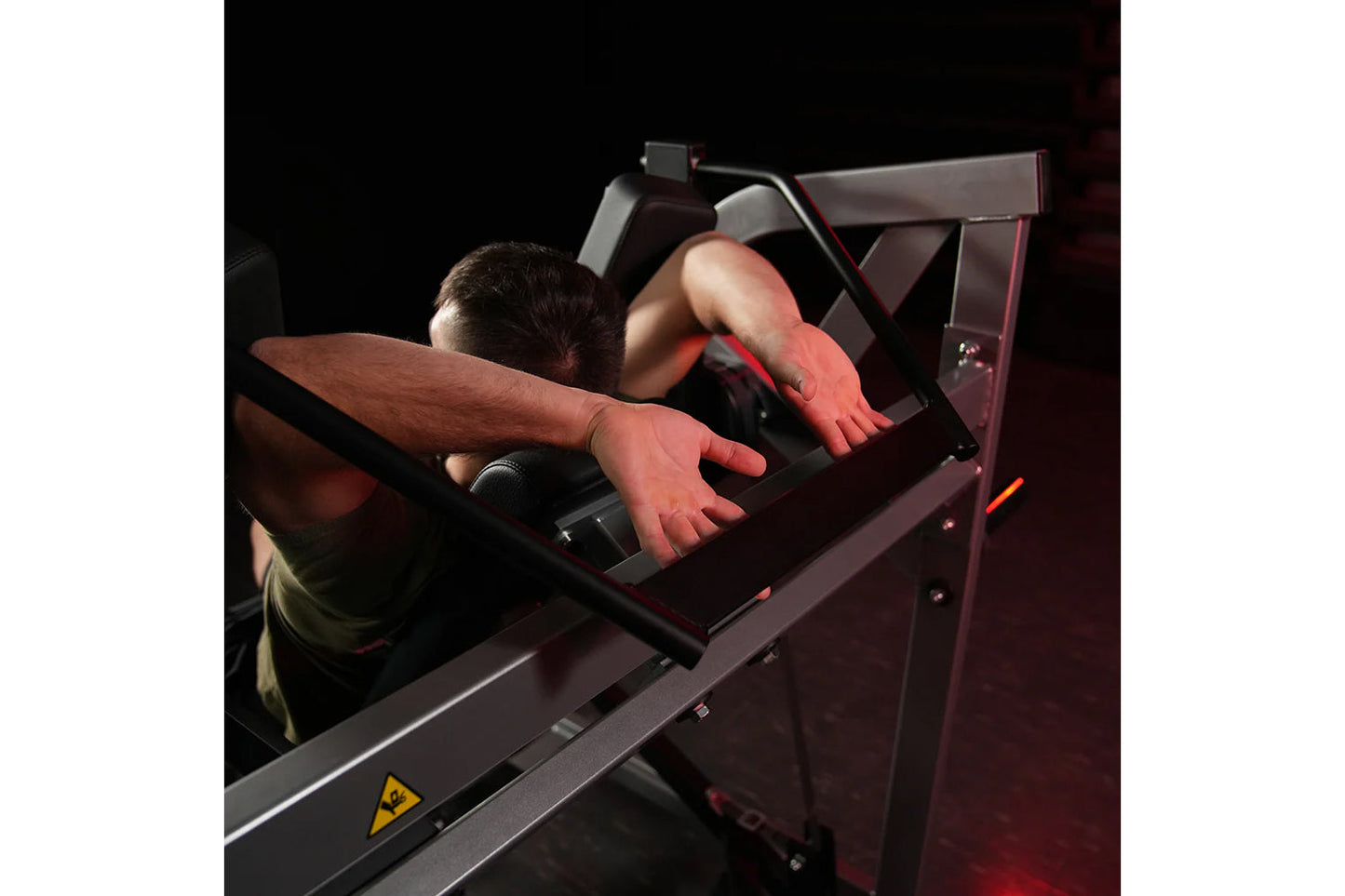 Man using burgundy Hammer Strength plate-loaded pullover machine with chest pad, demonstrating exercise position on black bac