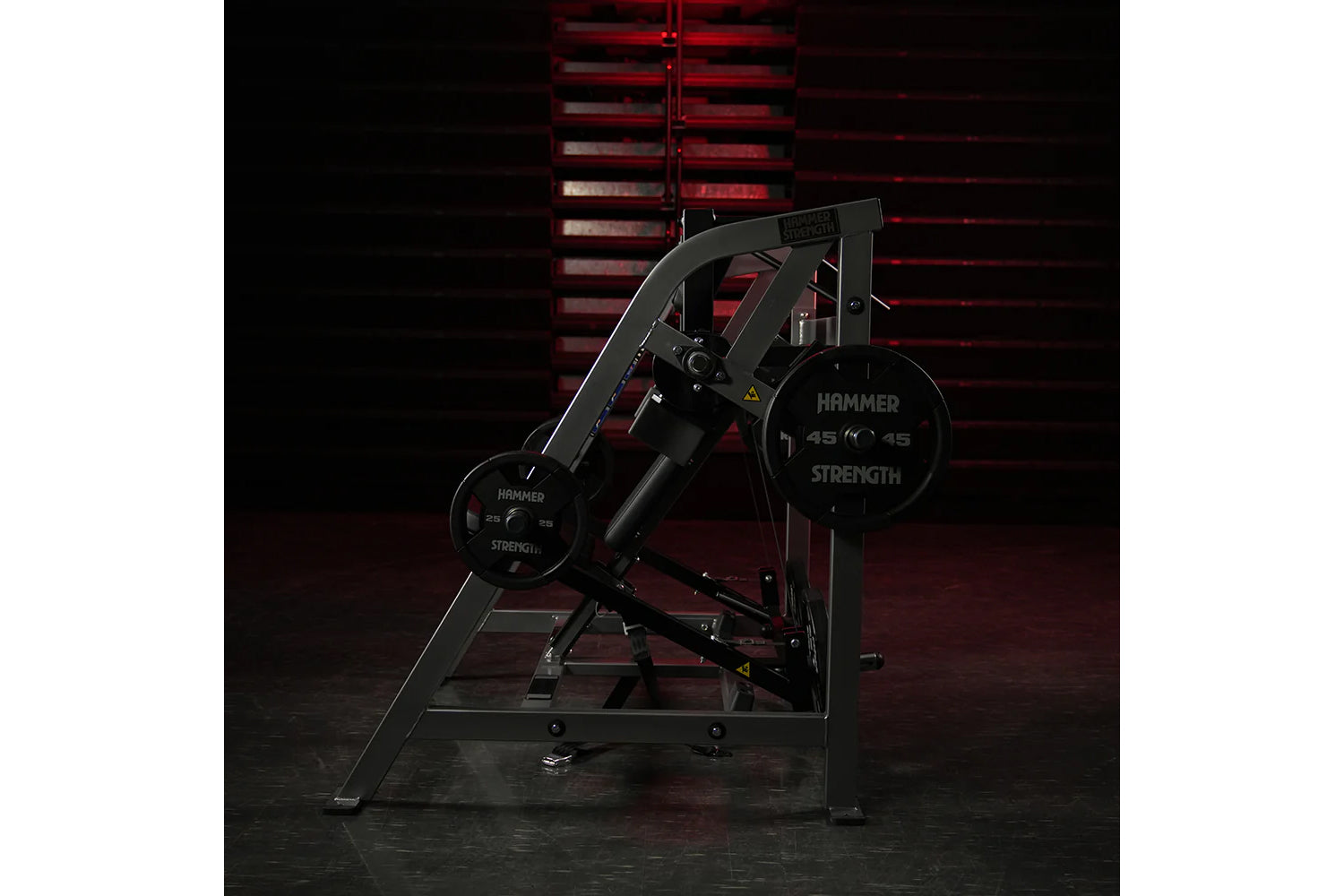 Hammer Strength black plate-loaded pullover machine with weight plates, in gym setting with red wall