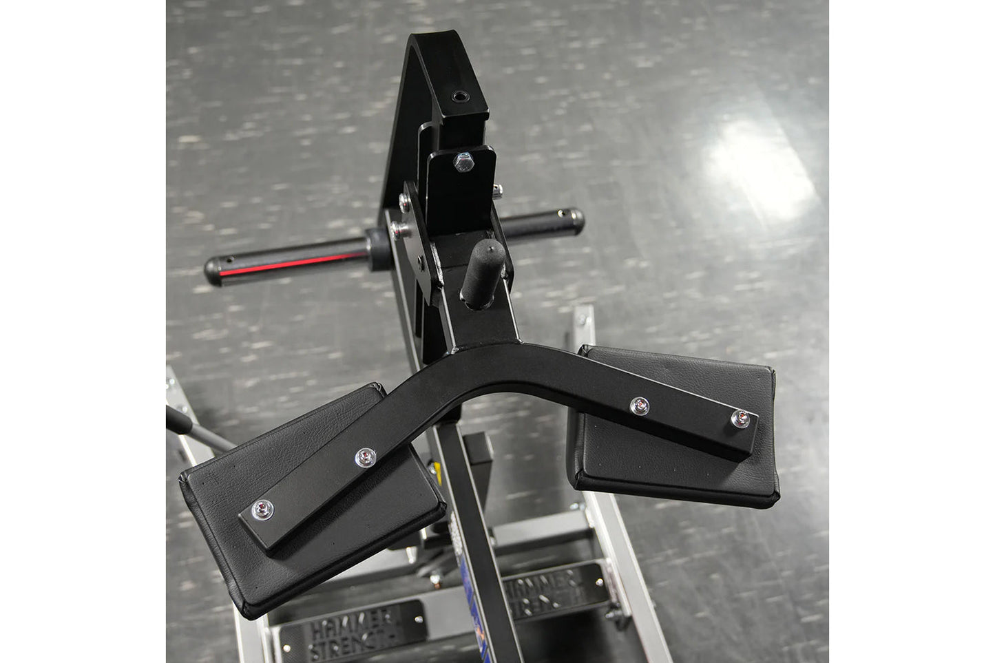 Hammer Strength plate-loaded seated calf raise machine with black padded foot platform and metal frame on gym floor