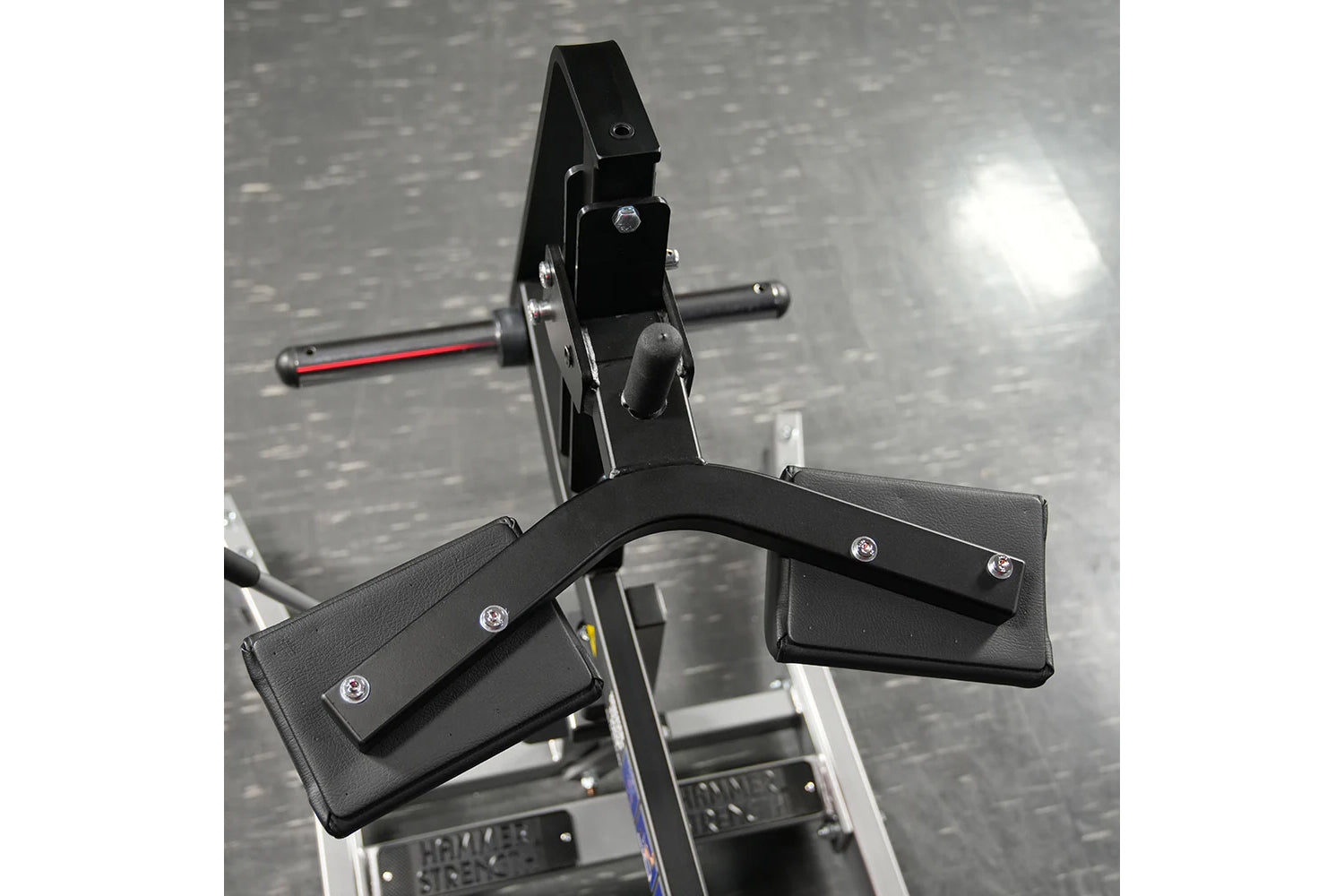 Hammer Strength plate-loaded seated calf raise machine with black padded foot platform and metal frame on gym floor