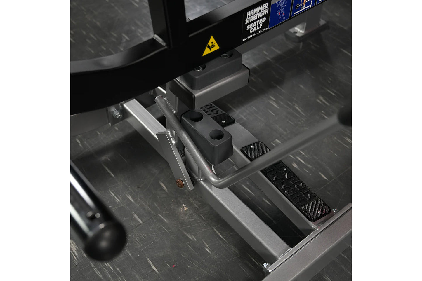 Hammer Strength plate-loaded seated calf raise machine with black frame, gray footplate, and dual foot pedals on gym floor