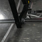 Black and chrome plate-loaded calf raise machine detail showing foot plate and adjustment pin connection