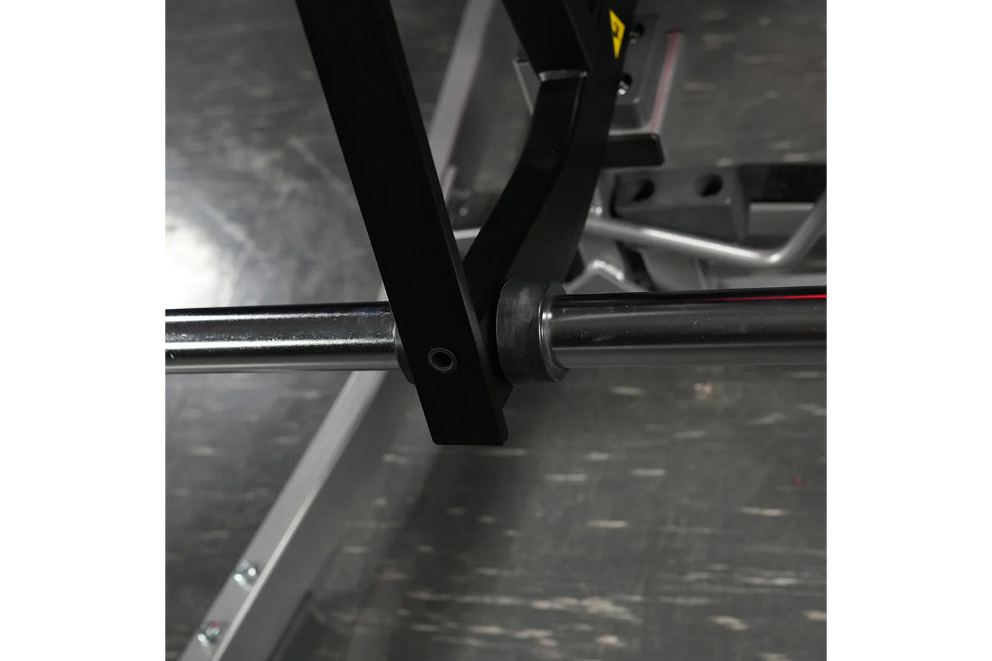 Black and chrome plate-loaded calf raise machine detail showing foot plate and adjustment pin connection
