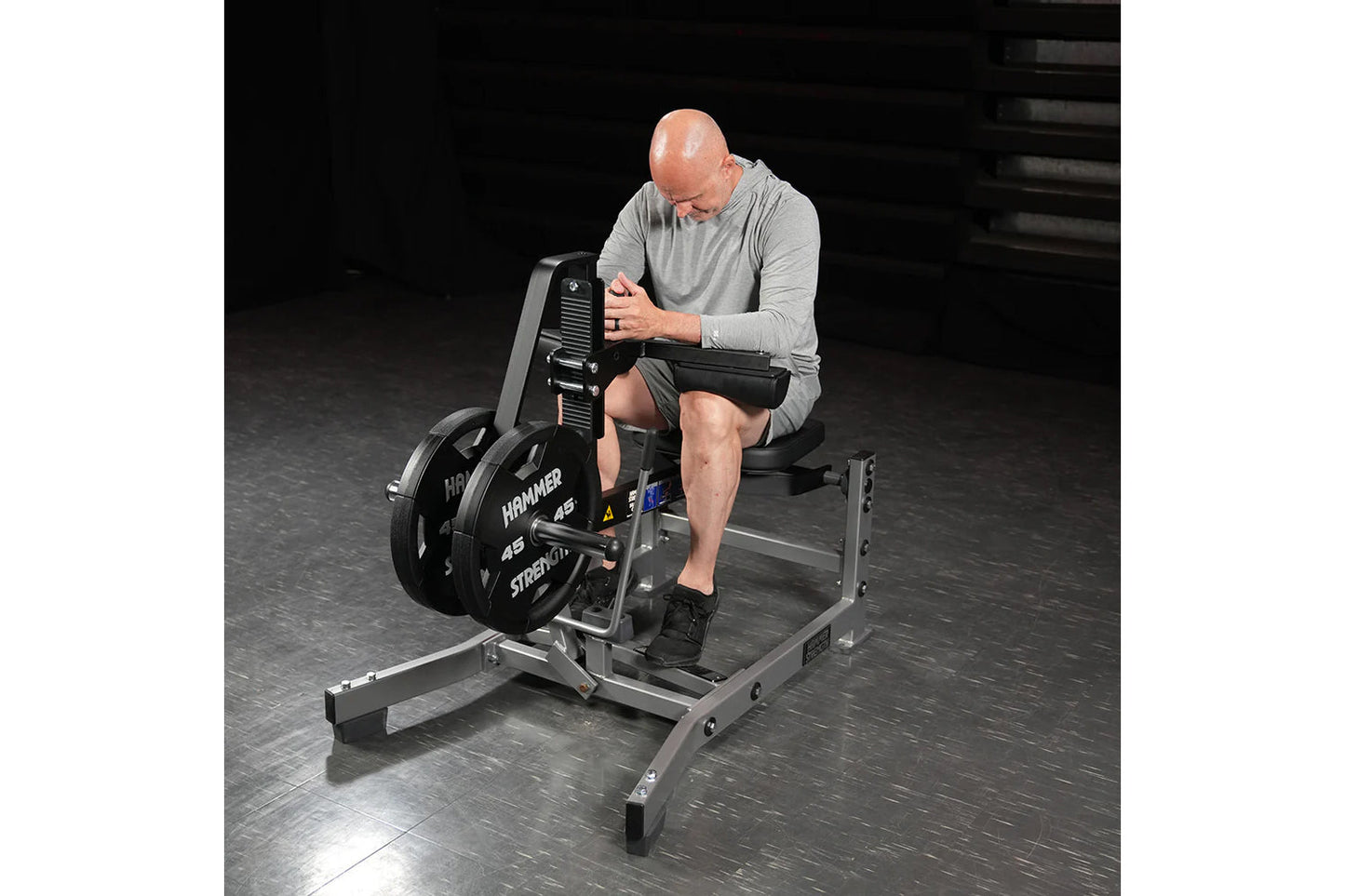 Man using Hammer Strength plate-loaded seated calf raise machine with black weight plates in gym setting