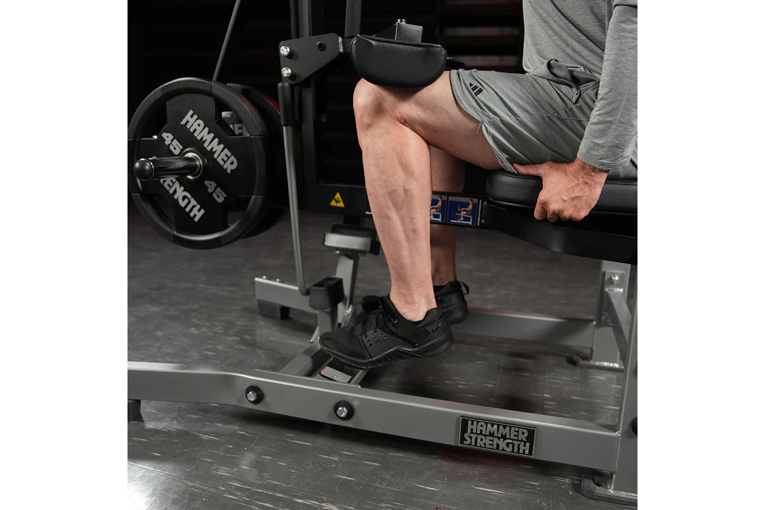 Man using Hammer Strength plate-loaded seated calf raise machine with black padding and weight plates