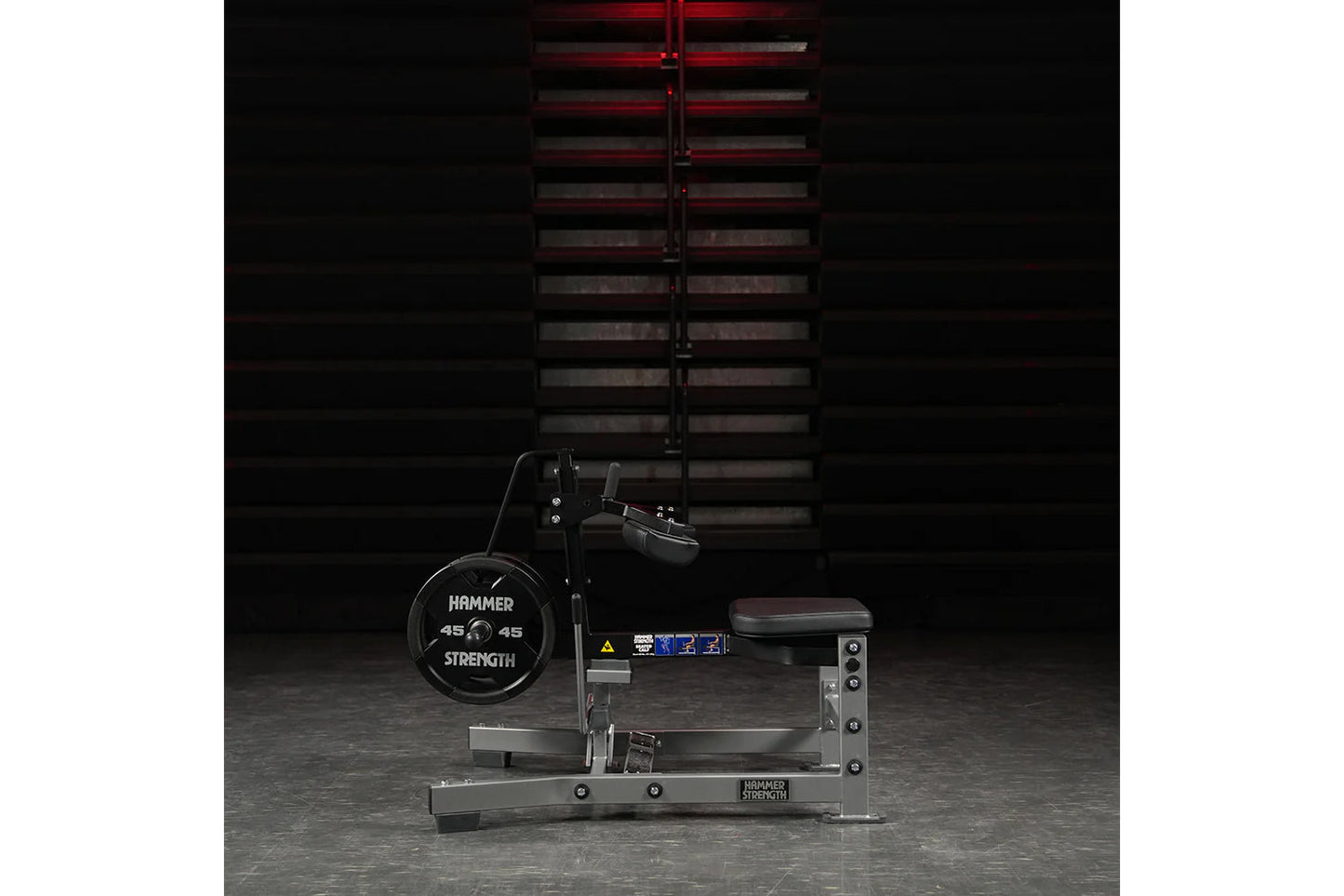 Hammer Strength plate-loaded seated calf raise machine with black 45-pound weight plates and red adjustable lever, shown on g