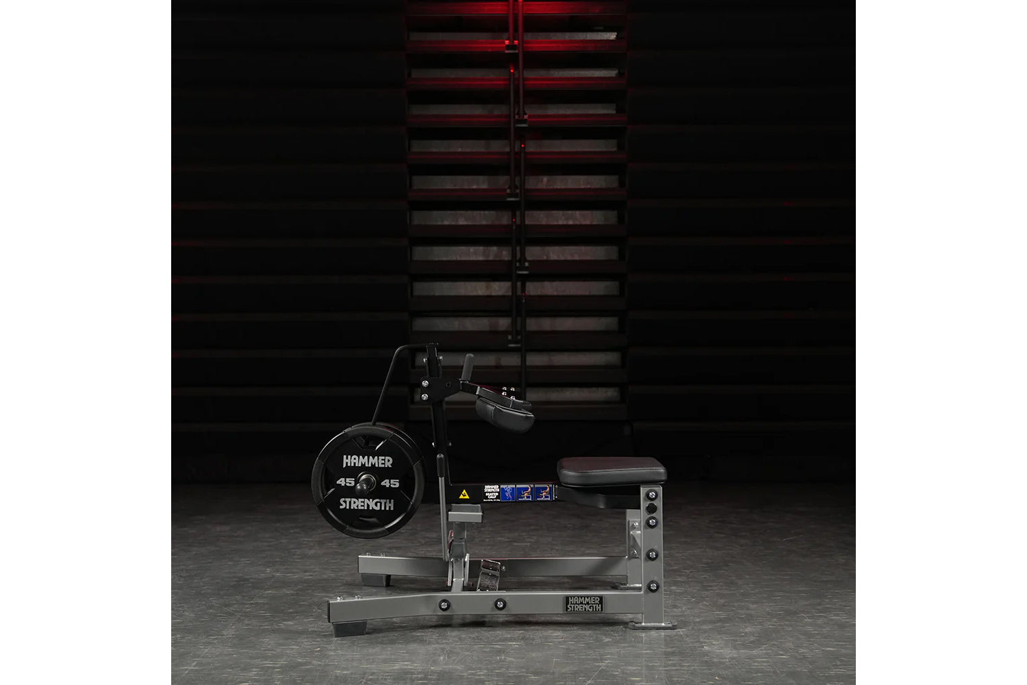 Hammer Strength plate-loaded seated calf raise machine with black 45-pound weight plates and red adjustable lever, shown on g