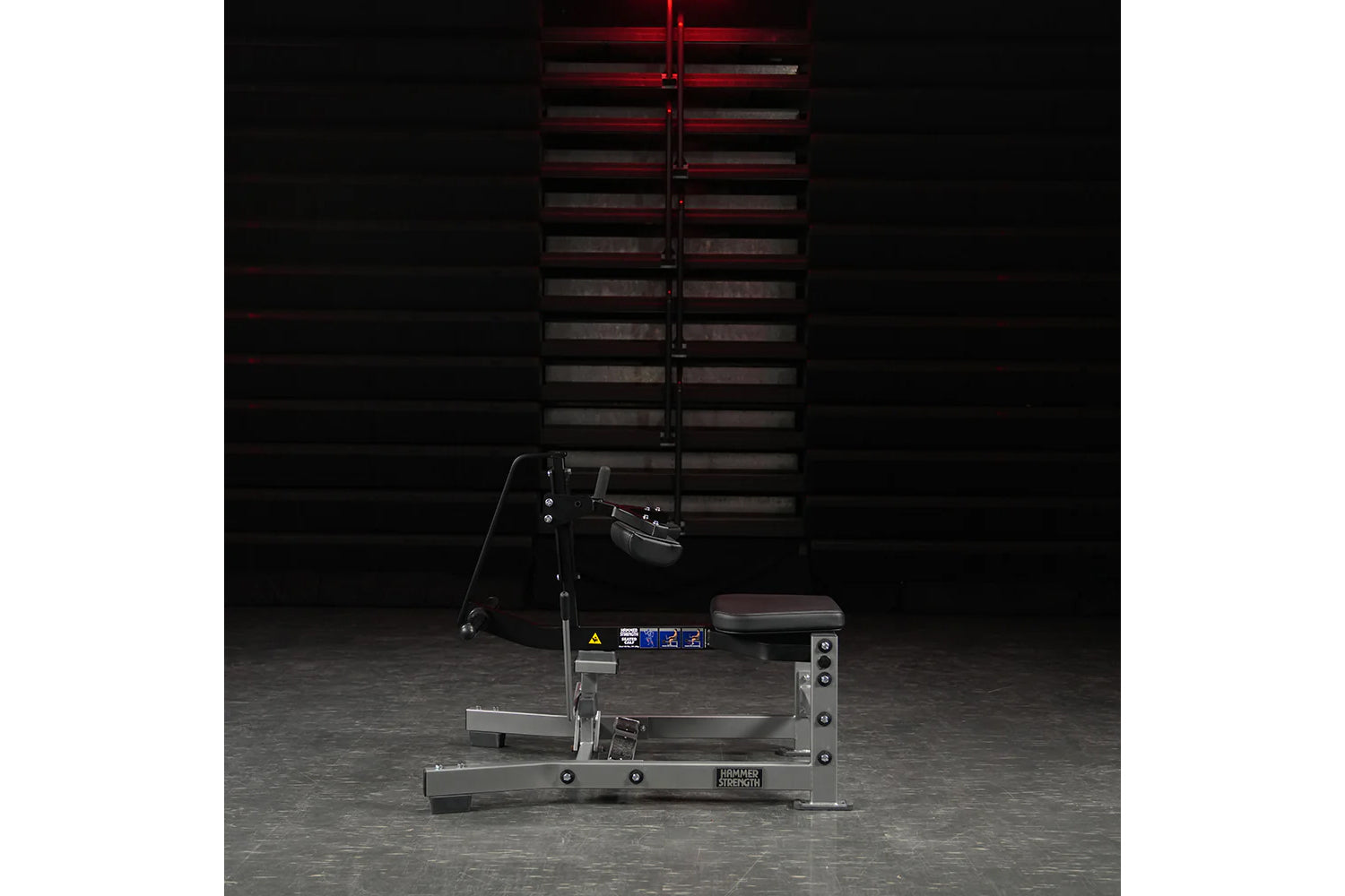Hammer Strength plate-loaded seated calf raise machine with black seat and gray metal frame, displayed in gym setting