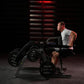 Man wearing gray tank top using Hammer Strength plate-loaded seated dip machine in gym with red lighting