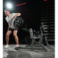Man wearing light gray t-shirt and black shorts performing squat high pull exercise on Hammer Strength plate-loaded machine i