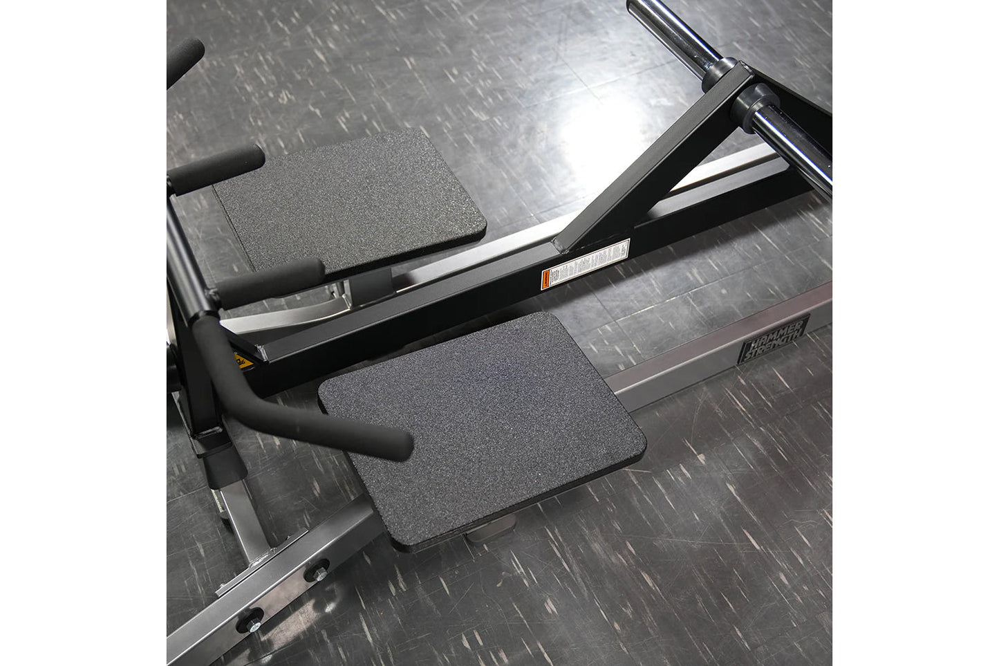 Hammer Strength plate-loaded T-bar row machine with black handles and gray textured foot platforms on diamond plate base
