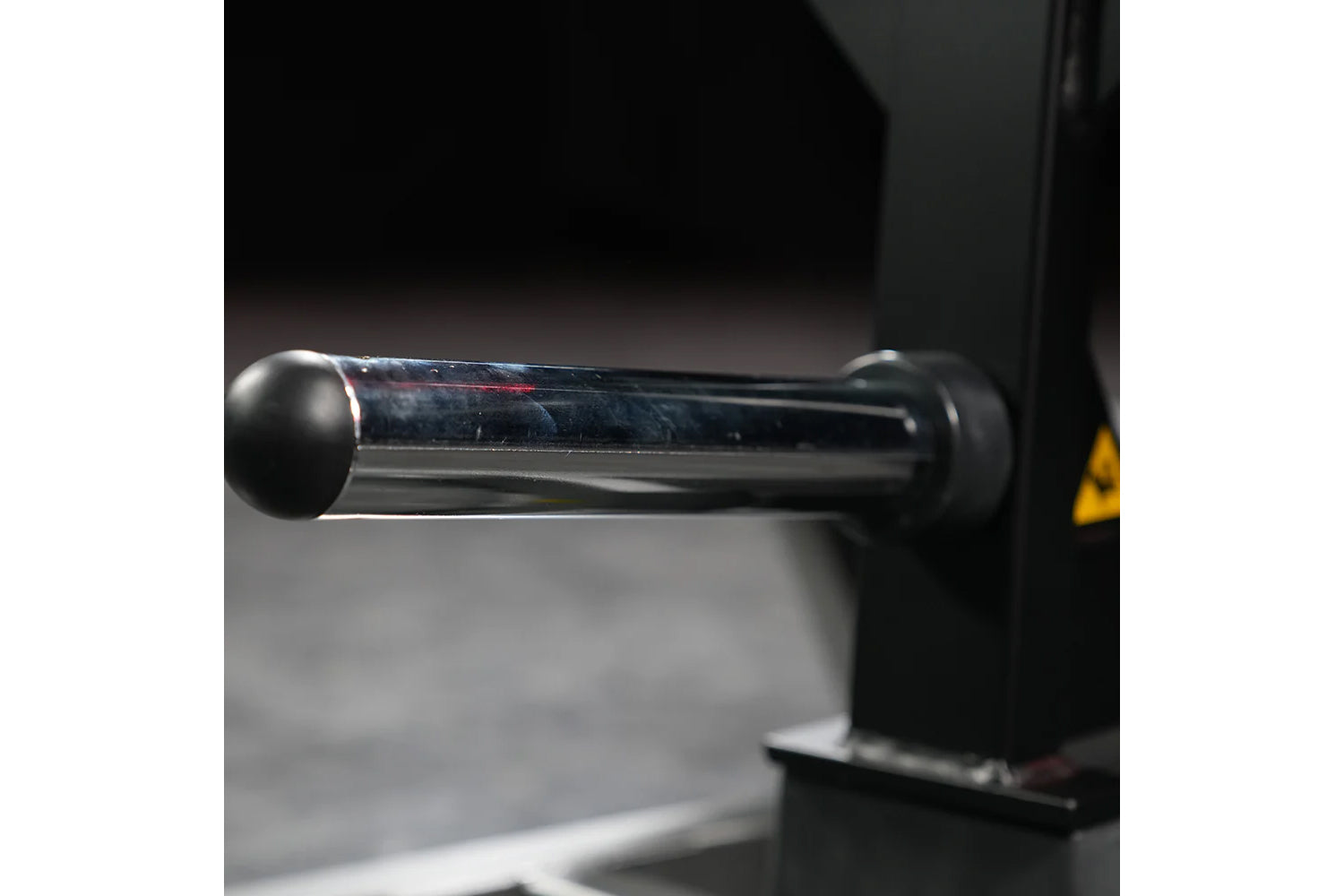 Black plate-loaded T-bar row machine with cylindrical steel bar and round grip handles on dark background