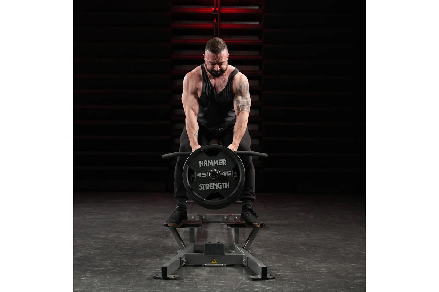 Muscular man in black tank top performing T-bar row exercise on Hammer Strength plate-loaded machine with 45-pound weight pla