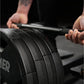 Person holding black plate-loaded T-bar row machine bar with textured grip and weight plates during workout