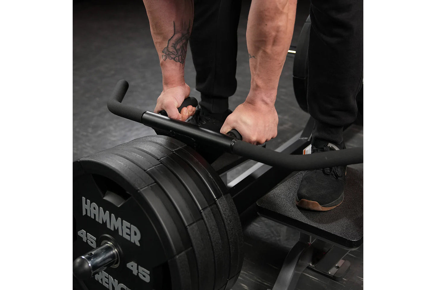 Person using Hammer Strength plate-loaded T-bar row machine with black weight plates and handlebar grip