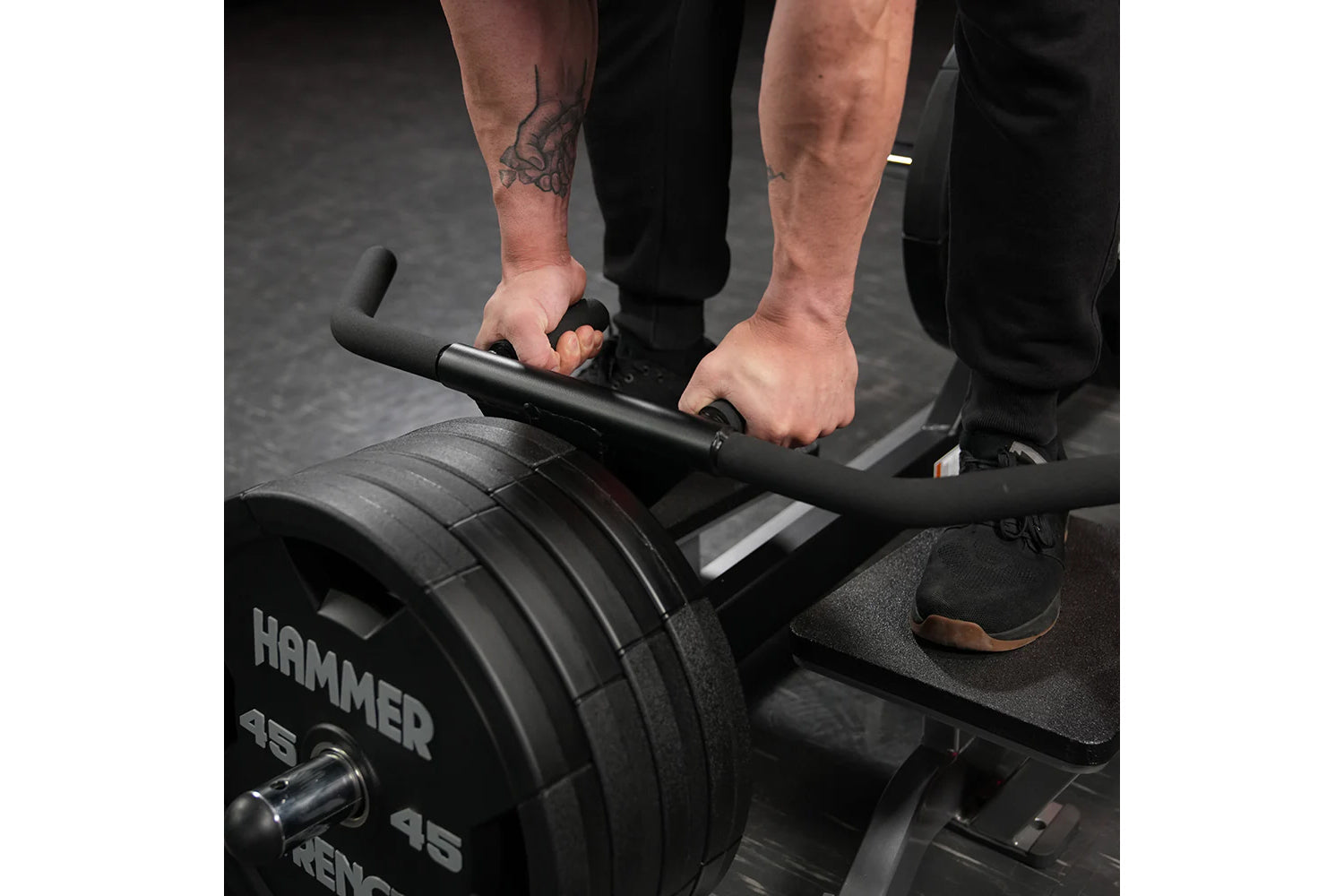 Person using Hammer Strength plate-loaded T-bar row machine with black weight plates and handlebar grip