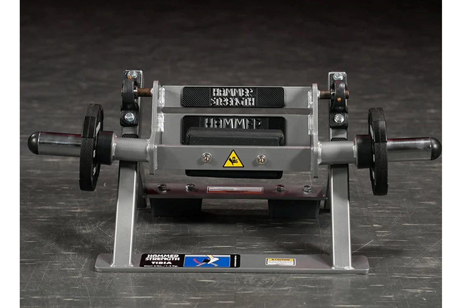 Hammer Strength plate-loaded tibia dorsi flexion machine with gray frame, black foot plates, and yellow caution symbol, front