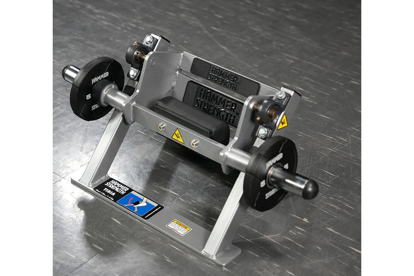 Hammer Strength plate-loaded tibia dorsi flexion bench machine with black weight plates and gray frame on dark background
