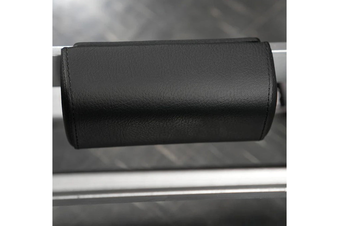 Black leather padded arm roll attachment for exercise machine, close-up view