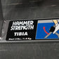 Hammer Strength Tibia machine label showing leg exercise illustration with start weight 3 lbs on dark background