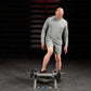 Man wearing gray long-sleeve shirt and shorts using Hammer Strength plate-loaded tibia dorsi flexion bench machine in gym set