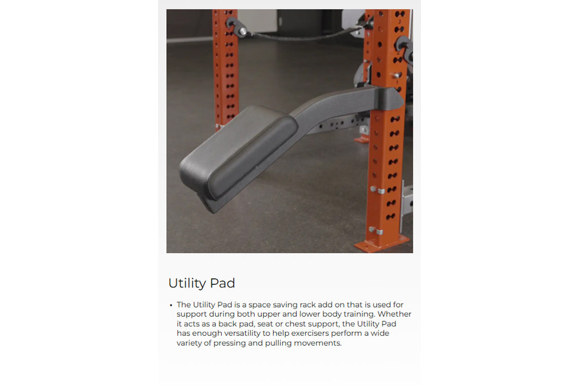 Gray and black curved utility pad attached to orange steel power rack frame in gym setting