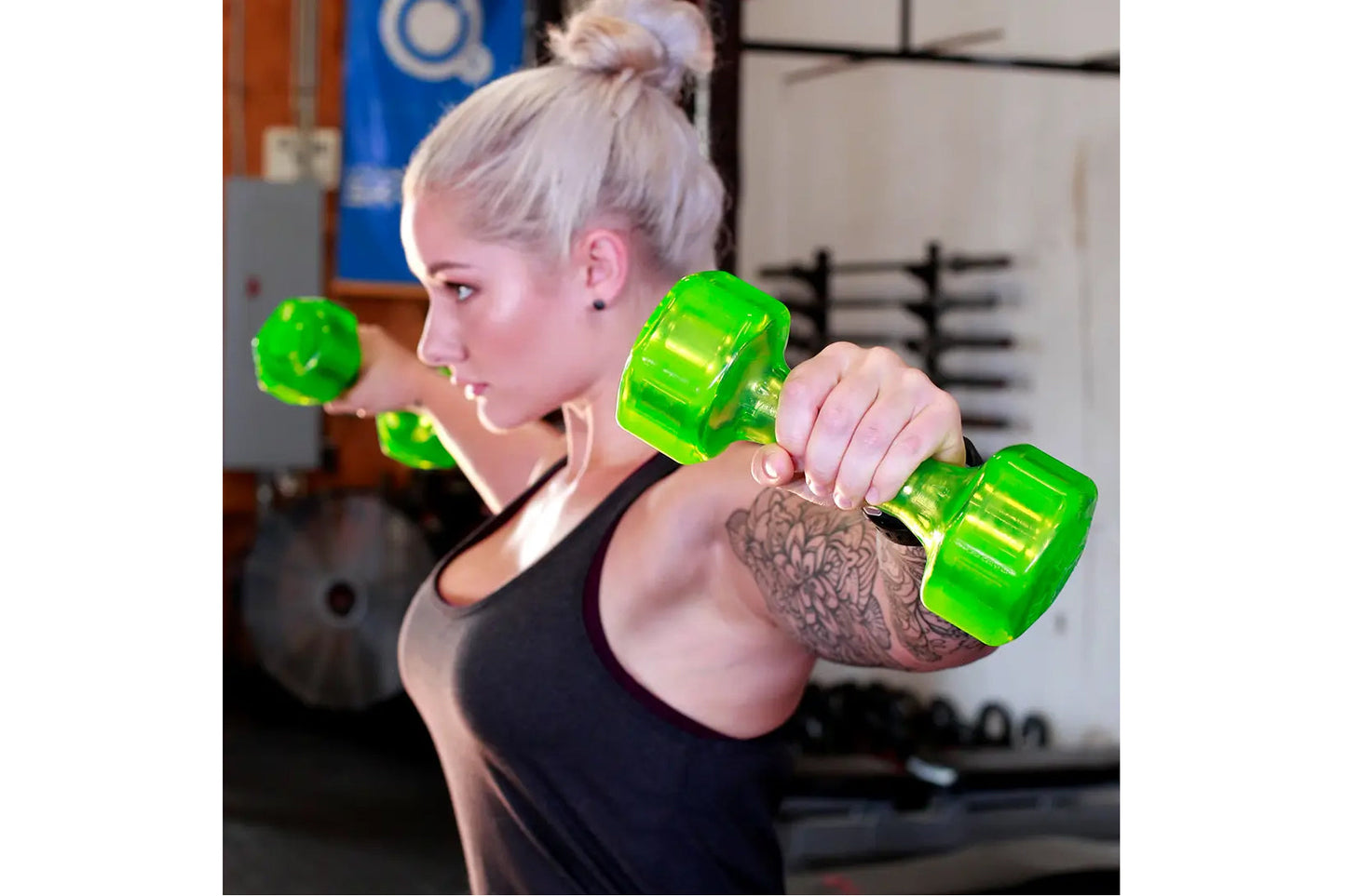 Woman lifting bright green translucent urethane dumbbells in a gym setting, wearing black sports tank top