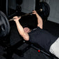 Man performing bench press with black Olympic barbell and weight plates on gym bench