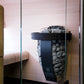 Harvia Spirit black electric sauna heater with gray stones and black metal frame mounted on pink wood wall in sauna enclosure