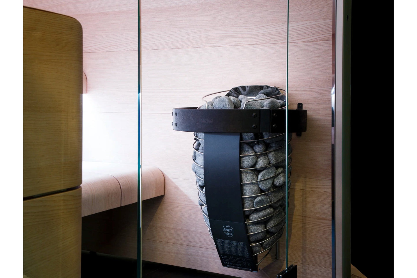 Harvia Spirit black electric sauna heater with gray stones and black metal frame mounted on pink wood wall in sauna enclosure