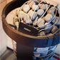 Harvia Spirit electric sauna heater with metal basket filled with gray saunas stones, black label visible on bronze container