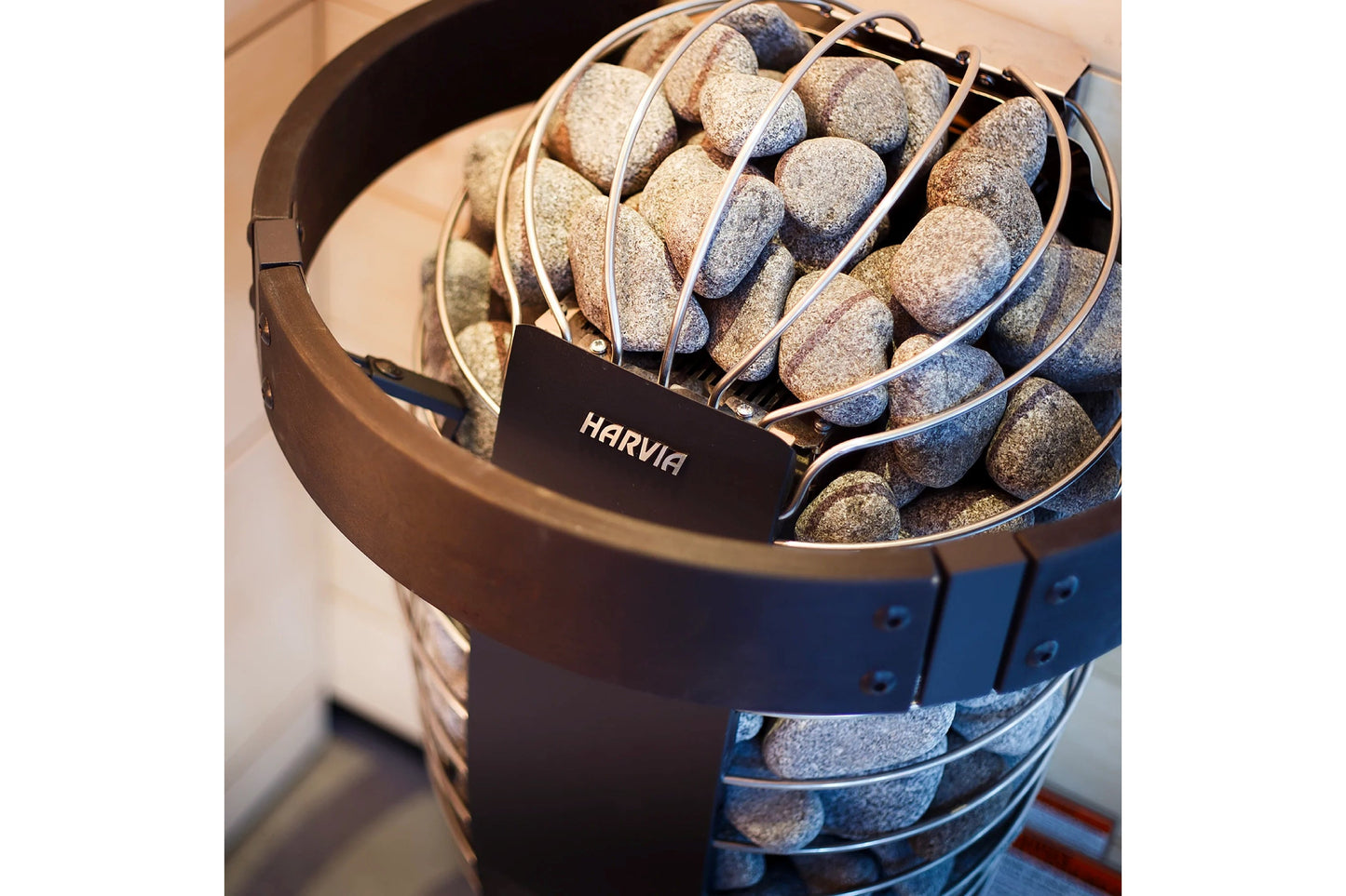 Harvia Spirit electric sauna heater with metal basket filled with gray saunas stones, black label visible on bronze container