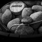 Harvia branded sauna stones in black metal ladle and bucket on dark background