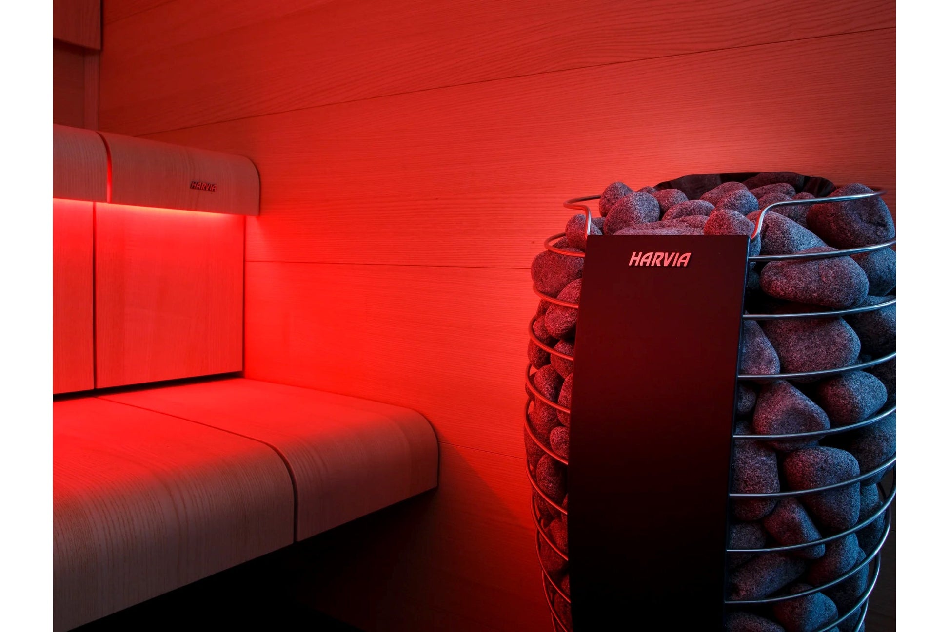 Harvia Spirit Electric Sauna Heater Package with red sauna room interior, wooden bench, and heated stones in cylindrical hold