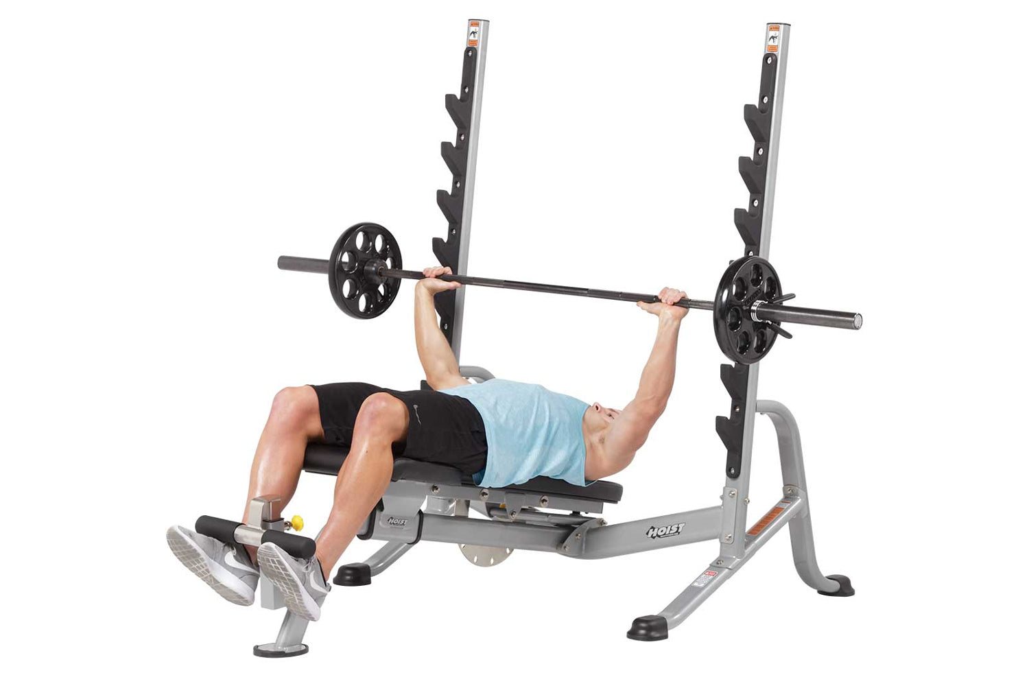 Hoist 7-Position Olympic Bench Press with black weight plates and bar, shown with model performing chest press exercise on gr