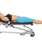Woman using silver and black Hoist weight bench with blue shorts and black sports top, demonstrating ab exercise position on 