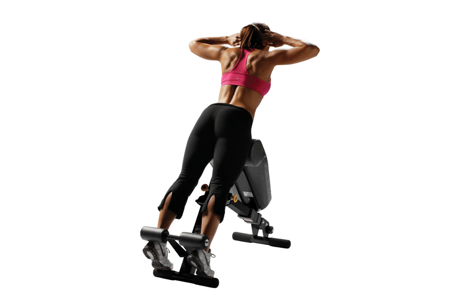 Woman performing abdominal exercise on black Hoist Ab/Back Hyper Bench, wearing pink sports bra and black leggings