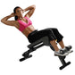 Woman in pink sports bra and black shorts performing abdominal crunch on black Hoist ab and back hyperextension bench against