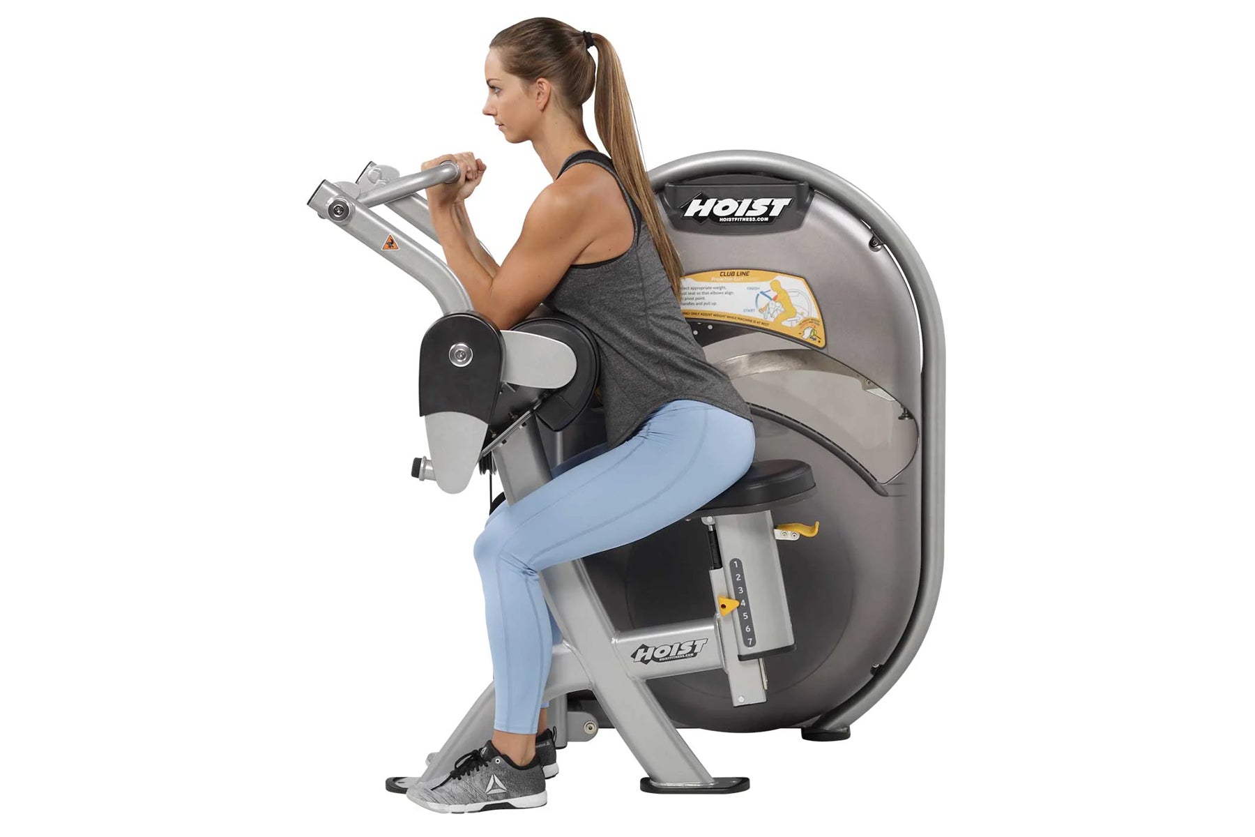 Woman using Hoist Biceps Curl machine with gray and black frame, demonstrating seated exercise position on white background